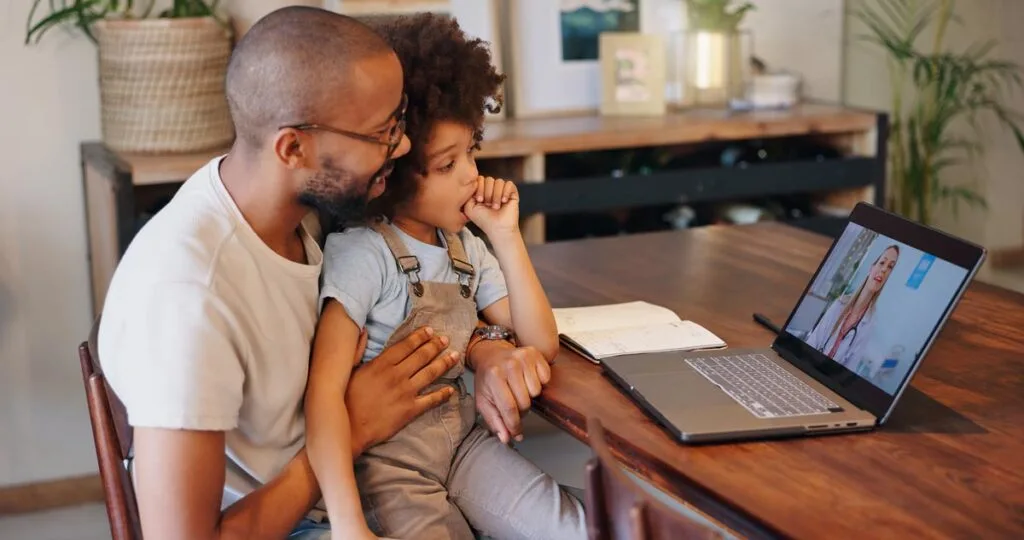 A father and daughter having a telehealth appointment with a pediatrician