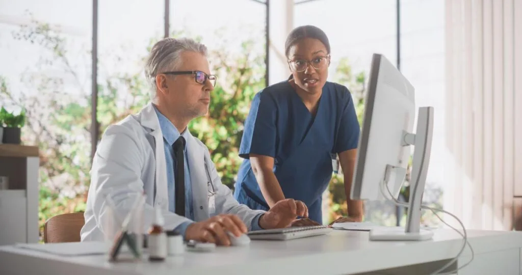 A doctor and nurse looking at a computer monitor