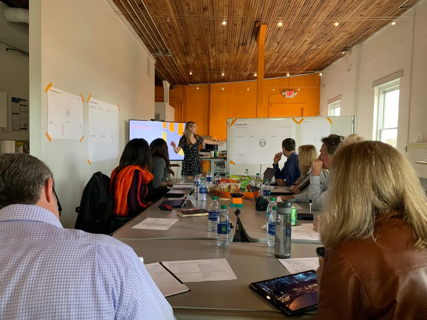 Design sprint workshop session with Holbrook stakeholders gathered around conference table, facilitator presenting research findings on whiteboards