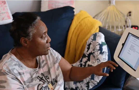 Woman using NeverAlone patient portal on tablet in care facility