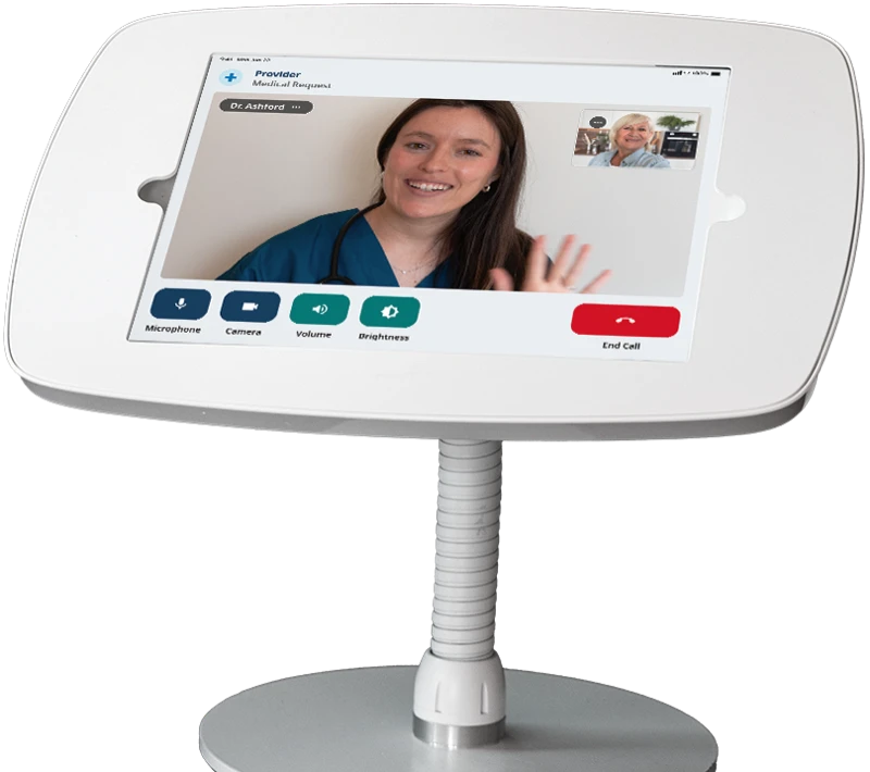 The NeverAlone device on a gooseneck stand, showing a live video call with a licensed provider and the resident in a picture-in-picture window