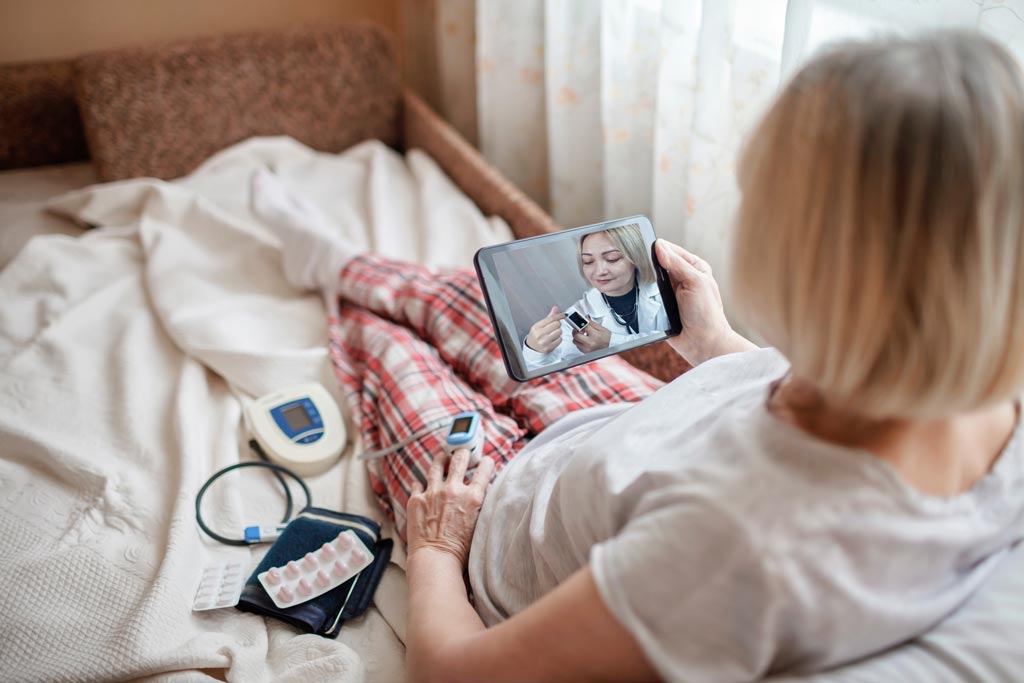 Remote patient monitoring: elderly woman video chats with doctor while testing vitals with connected IoT devices