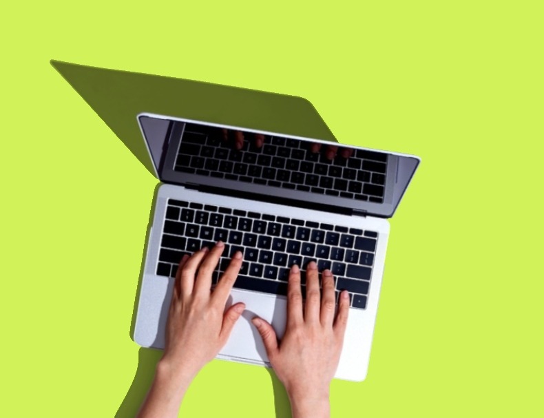hands typing on laptop green